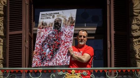 Ángel Blanco posa en el balcón del Ayuntamiento de Pamplona con su obra *Gaiteros", el cartel ganador que anunciará los Sanfermines 2024