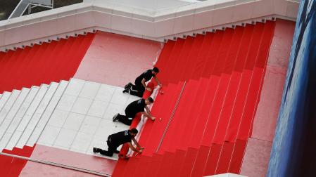 Trabajadores instalan la alfombra roja antes de la ceremonia de apertura del 77º Festival de Cine de Cannes