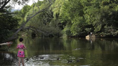 Una niña junto al río Arga a su paso por la Magdalena, en Pamplona.