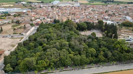Imagen aérea del parque municipal de Cortes, con la plaza para actos en su interior y, al fondo, el castillo y núcleo urbano de la localidad ribera