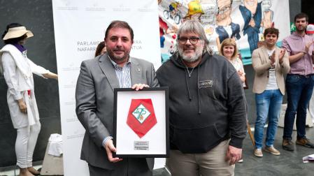Carmelo Butini y Eider Bueno entregaron un pañuelo de la Peña Anaitasuna enmarcado al presidente del Parlamento, Unai Hualde, el último obsequio registrado en el Legislativo, con motivo de la exposición por el 75 aniversario de esa peña