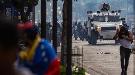 Manifestantes corren durante enfrentamientos entre opositores y miembros de la Guardia Nacional Bolivariana (GNB), por los resultados de las elecciones presidenciales este lunes, en Caracas