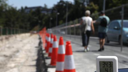 Una pareja de Burlada baja por el paso habilitado para peatones en la cuesta de Beloso. El termómetro marca 34,3°