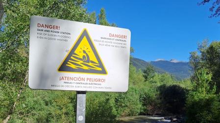 Cartel de peligro bañarse por el riesgo de crecida súbita del río porque estar cerca de una presa