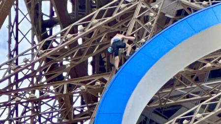 Un hombre escala la torre Eiffel
