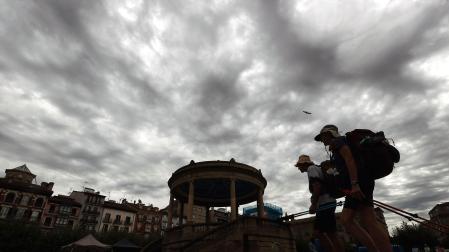 Dos turistas pasean por la Plaza del Castillo de Pamplona con un cielo tormentoso este jueves