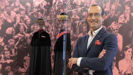 El investigador y coordinador general de la Asociación de Amigos de la Universidad de Navarra, Manuel Vilches, junto a las vestes académicas expuestas en el hall de Rectorado