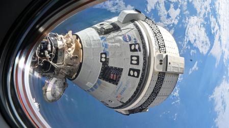 Fotografía tomada desde una ventana de la nave espacial SpaceX Dragon Endeavour donde se muestra a la cápsula Straliner de Boeing acoplada al puerto delantero del módulo Harmony