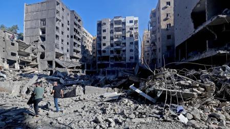 La gente camina entre los escombros de los edificios destruidos después de los ataques aéreos israelíes en el suburbio del sur de Beirut, Líbano, este domingo