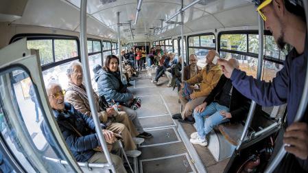 El actor en el papel de conductor muestra un antiguo billete ante los visitantes a la villavesa del Bosquecillo