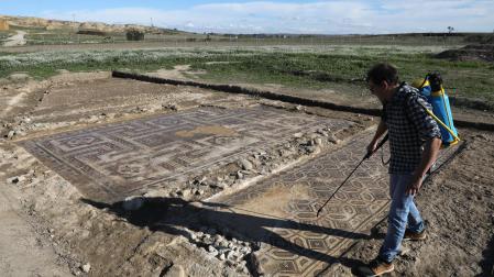 Alex Duró mojando los dos mosaicos descubiertos por completo en Campo de Arlas, el yacimiento arqueológico de Peralta