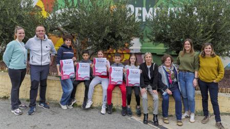 Desde la izda., Samantha Echarri Michelena, jefa de estudios de PAI; Unai Díez Cía, tutor en el modelo D; Izaro Puy Crespo, profesora de euskera; Eros Crespo Loján, alumno de 6º de Primaria de PAI; Iranzu Vidán Yanci, alumna de 6º de PAI; Aiur Nuin Olite, alumno de 6º de modelo D; Laia Garro Mínguez, alumna de 6º en modelo D; Piluca Ochoa Azcona, logopeda del centro; Enkarni Valencia García, tutora en modelo D; Elena Jiménez Herce, tutora en PAI; y Amaia Arbizu Calanda, jefa de estudios del modelo D con los carteles de la fiesta del 50 aniversario