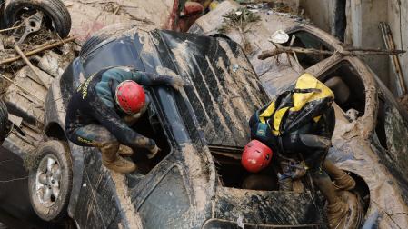 Expertos de la Guardia Civil buscan cuerpos sin vida entre los vehículos atrapados entre los cimientos de un edificio en construcción, este sábado en Paiporta