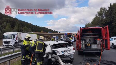 Efectivos de bomberos, junto a un vehículo implicado en el siniestro