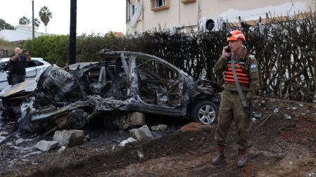 Un soldado israelí se encuentra cerca de un automóvil dañado en el lugar después de que un cohete disparado desde el Líbano impactara en un barrio residencial en Petah Tikva, en el centro de Israel