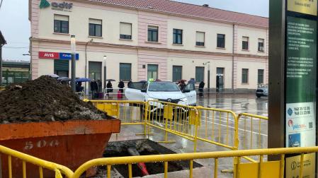 Una cola de pasajeros espera a un taxi bajo la lluvia en la estación de tren de Pamplona. En primer plano, las obras para construir una pérgola para resguardarse
