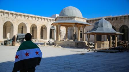 Un hombre con la bandera de los rebeldes sirios, en la Gran Mezquita de Aleppo
