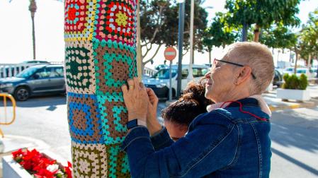 Dos de las vecinas de la localidad colocan una de las obras en un árbol /