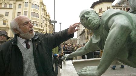 El escultor Rafael Huerta señala su propia imagen en el grupo escultórico del Encierro instalado en la Avenida Roncesvalles