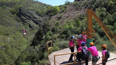 Un grupo de personas aguarda en una plataforma del parque de aventuras para lanzarse por unas tirolinas.