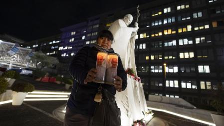 Una mujer sujeta dos velas con la imagen del papa Francisco ante el hospital Gemelli de Roma donde está hospitalizado /