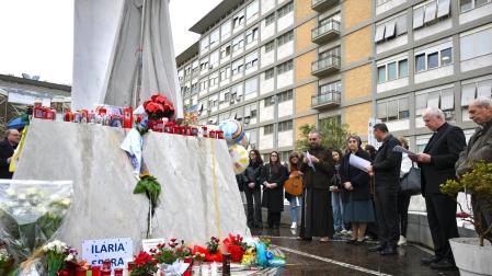 Rezos y flores por el papa junto a la estatua de Juan Pablo II en el exterior del hospital Gemelli de Roma