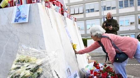 Una mujer deposita flores a los pies de la estatua de Juan Pablo II, en el exterior del hospital Gemelli, donde continúa ingresado el papa Francisco