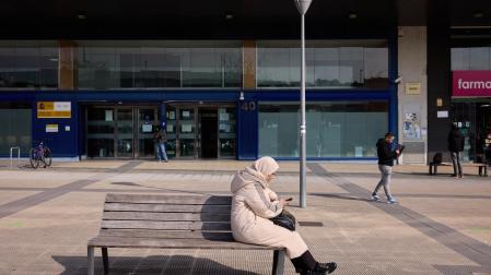 Una mujer consulta su móvil en las inmediaciones de la oficina de Extranjería de Pamplona