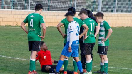 El árbitro, en el suelo con una herida en el labio, junto a jugadores de ambos equipos que se interesan por él