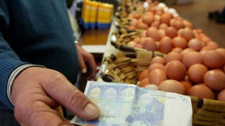 Una persona usa un billete de 20 euros para comprar huevos