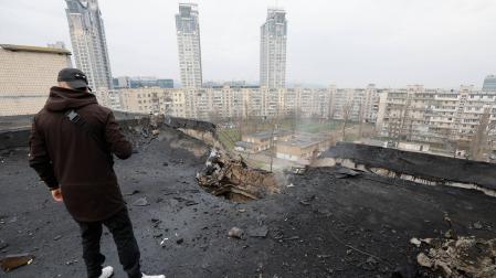 Un hombre inspecciona los daños causados por un ataque nocturno de drones en el tejado de un edificio residencial en Kiev