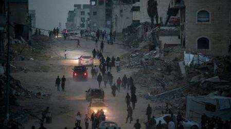 Palestinos caminan por una calle cerca de los escombros de los edificios destruidos tras huir del norte de Gaza tras una orden de evacuación del ejército israelí, en la ciudad de Gaza