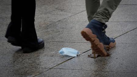 Un hombre camina por Pamplona con una mascarilla tirada en el suelo