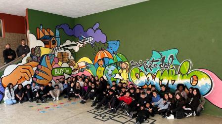 El alumnado de 3º de la ESO con el mural pintado en un rincón del patio con el que invita a reflexionar sobre las compras