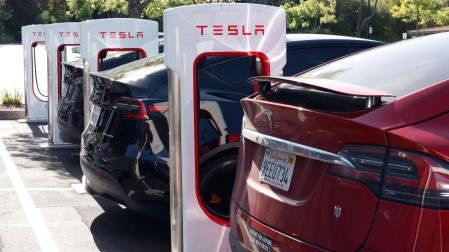 Varios vehículos Tesla cargándose, uno de ellos con la pegatina que avisa de que su propietario compró el coche antes de que Elon Musk se volviera loco