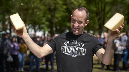 Jesús Zelaieta muestra las mitades del queso recién cortado en la feria de primavera.