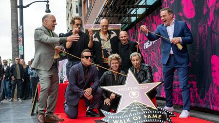 Los miembros de Green Day Tre Cool, Billie Joe Armstrong y Mike Dirnt observan cómo se revela su estrella durante la ceremonia en el Paseo de la Fama de Hollywood en honor a la banda