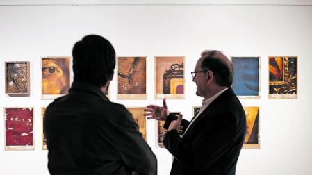 El artista de espaldas y un visitante observan la exposición en la Casa de Cultura de Zizur Mayor