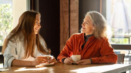 Una madre y su hija hablan mientras toman un café