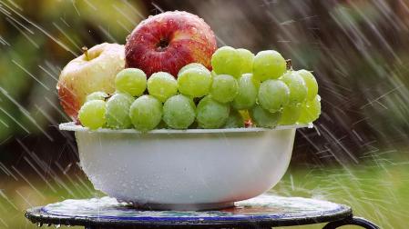 Un frutero con manzanas y uvas