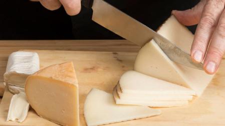 Imagen de archivo de una persona cortando queso