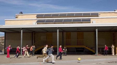 Varios niños juegan en el patio de recreo de la Ikastola Hegoalde con placas solares en el techo de las instalaciones /