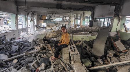 Un niño palestino descansa sobre los restos de la escuela bombardeada en Gaza City