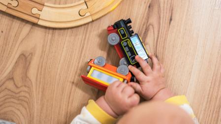 Bebé jugando con un tren de madera.
