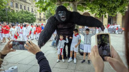 Un orangután de grandes dimensiones posa junto a tres niños que le hacen cosquillas el sábado por la mañana en Pamplona.