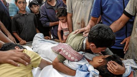 Un niño palestino se despide de su hermano fallecido en el bombardeo israelí contra el punto de distribución de agua en Nuseirat