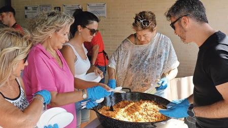 Varias personas colaboraron en el reparto de migas, pinchos de txistorra y vino y agua junto al edificio de usos múltiples de Mélida