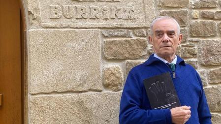 Jesús Alegría en la puerta de su casa natal de Artazu con un ejemplar de su diccionario en las manos