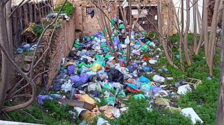 Imagen de las bolsas de basura y demás restos acumulados en el interior del solar situado entre las calles Cortes y Magallón de Tudela