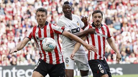 El delantero nigeriano del Valencia Umar Sadiq, autor del gol de su equipo, disputa el balón ante Andoni Gorosabel y Mikel Vesga, del Athletic